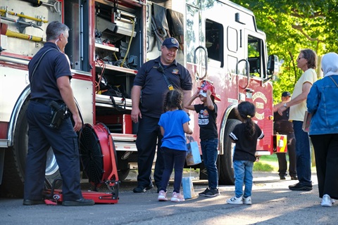 Photo of Public Safety Offices interacting with children in front of a fire engine